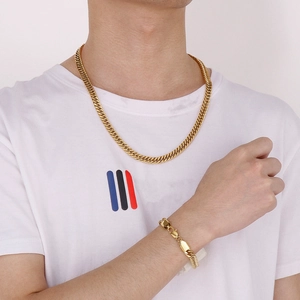 Close-up of golden Cuban link chain necklace and bracelet set on a male model wearing a white tee
