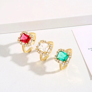 Bagues luxueuses avec zircons carrés en rouge, clair et émeraude sur monture dorée