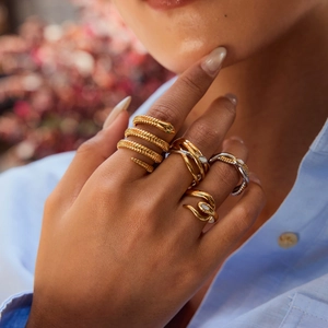 Elegant gold snake ring with green stone eyes and multi-layered interwoven steel design
