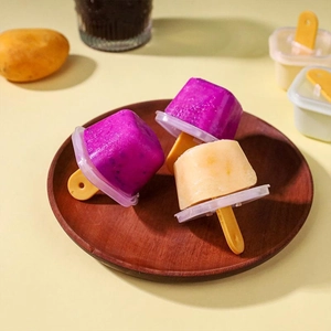 Detail of homemade fruit popsicles in a yellow mold with lids on a wooden tray