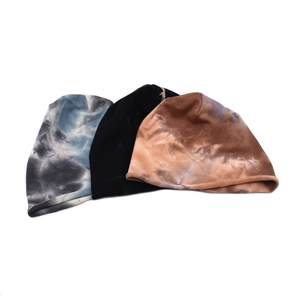 Three tie-dye slouchy beanies in blue-grey, black, and brown on a white background