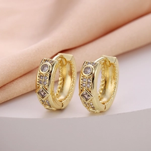 Macro detail of 18K gold hoop earrings featuring round and square cubic zirconia stones