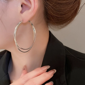 Détail de vue latérale d'un modèle portant des boucles d'oreilles créoles doubles en argent