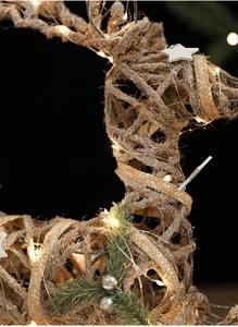 Macro detail of lighted woven reindeer decoration with silver glitter and warm LED glow
