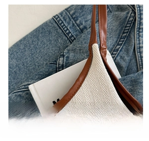 Détail de la texture en toile chevron et des coutures en cuir marron sur le sac cabas
