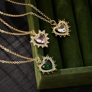 Three elegant gold necklaces with heart starburst pendants in white, pink, and green zircon