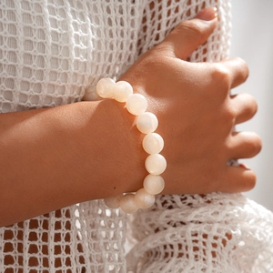Detail of elegant white acrylic beaded bracelet showing polished round beads on wrist