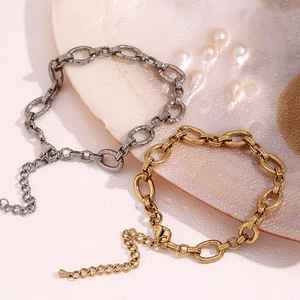 Detail view of 14K gold and silver retro large O-chain anklets on a decorative shell tray