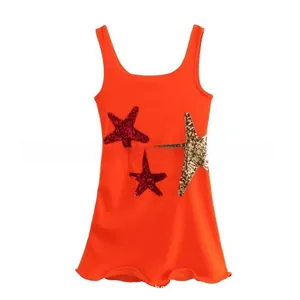 Detail of red sleeveless dress featuring sparkling sequined stars and ruffle hem details