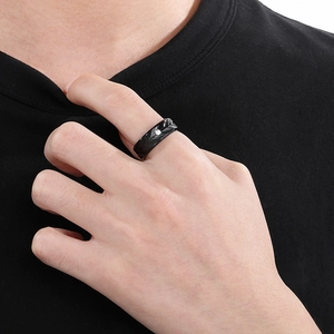 Detail of men's black stainless steel ring featuring feather texture and center crystal