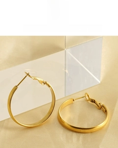 Macro view of 18K gold plated minimalist stainless steel hoop earrings on silk background