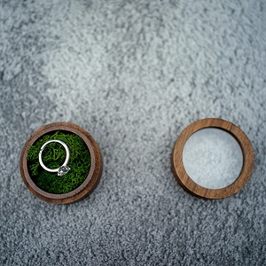 Detail view of round black walnut wood ring box with clear lid and green moss lining