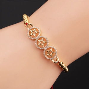 Detailed shot of a gold-plated bracelet featuring three crystal-encrusted star charms on a red cord