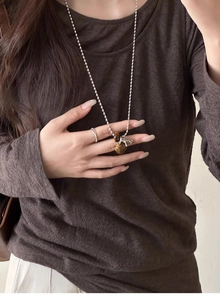 Close-up of a silver pony pendant necklace featuring tiger eye stones on a woman