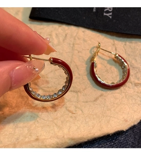 Macro view of C-shaped 14K gold plated earrings with red enamel and pavé crystals