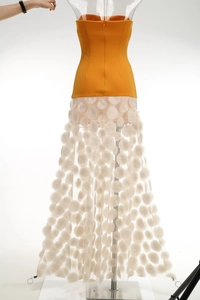 Detailed view of yellow strapless bodice with white polka dot mesh layered skirt
