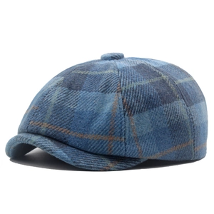 Dettaglio del berretto newsboy a quadri blu con tessuto in misto lana e bottone decorativo