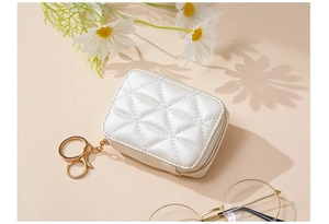 Detail of white quilted cosmetic bag with gold zipper and hook on warm background