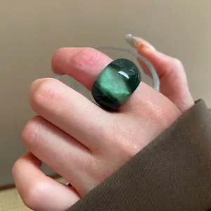 Minimalist geometric resin oval ring with emerald green marble effect on female finger