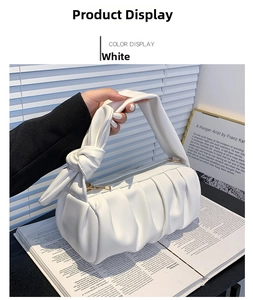 Detail of white ruched cloud bag with a unique knotted handle and gold metal zipper