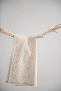 Détail d'une serviette en lin avec motifs de flocons dorés suspendue sur bois
