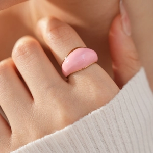 Macro detail of a pink enamel domed ring with gold trim on a female model's finger