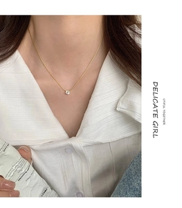 Close-up of a delicate gold chain necklace with a single round zircon pendant for women