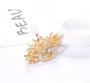 Detail showing vintage eye brooch dual-use as necklace with yellow diamond and gold texture