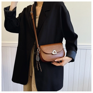 Detail of vintage brown PU leather crossbody bag with heart buckle and tennis charm