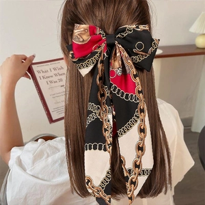 Detailed view of a large vintage bow hair clip with chain print on a model's hair