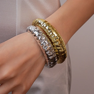 Detailed close-up of textured gold and silver irregular hammered metal bracelets