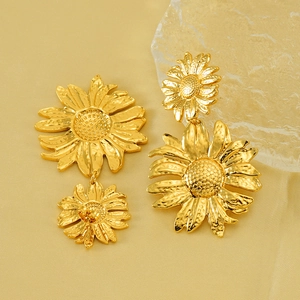 Textured gold sunflower earrings with hammered finish shown on an elegant silk background