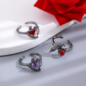 Detailed view of three gothic rings set with heart gems and black thorn designs