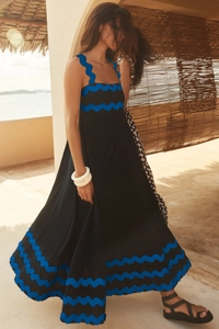 Detail view of black summer maxi dress with blue scalloped edges in a tropical beach setting