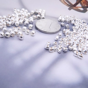 Macro shot of silver geometric beads on purple background for DIY jewelry making