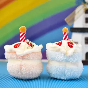 Detailed macro view of two colorful mini plush cake pendants with candles and metal straps.
