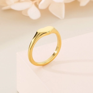 Polished heart signet ring in gold finish placed on a minimalist geometric display