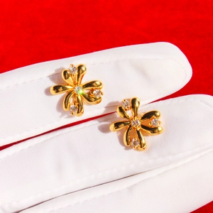 Exquisite gold floral stud earrings with zircon inlay on a red velvet background