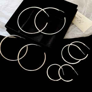 Detailed view of silver hoop earrings in various sizes on elegant black velvet background