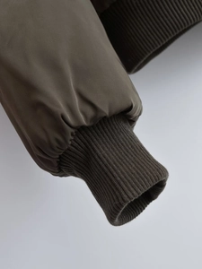 Detailed close-up of ribbed cuffs and twill fabric texture on a green bomber jacket