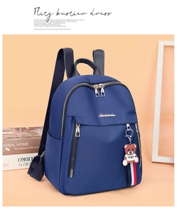 Detail view of water-resistant navy nylon backpack with side bear charm and metal logo
