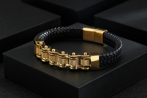 Macro shot of black braided leather bracelet with golden chain and magnetic buckle