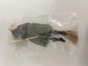 Hanging witch doll with green mesh skirt and broomstick in protective plastic packaging