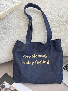 Navy blue denim tote bag with yellow embroidery text on white textured surface