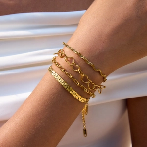Detail view of four-piece gold stainless steel layered bracelets on female wrist