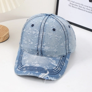 Distressed light blue denim baseball cap with vintage ripped details and frayed brim style
