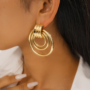 Close-up of oversized gold geometric hoop earrings with polished multi-circle design