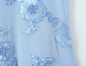 Vue macro de broderies florales 3D bleu ciel sur tulle pour robe de soirée à corset