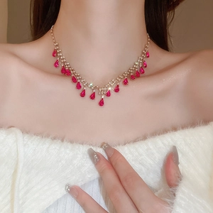 Detailed view of gold tassel necklace with rose red teardrop gems on female model