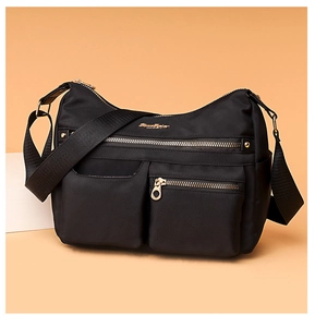 Close-up of black water-resistant nylon shoulder bag with gold zipper and multi-pocket detail